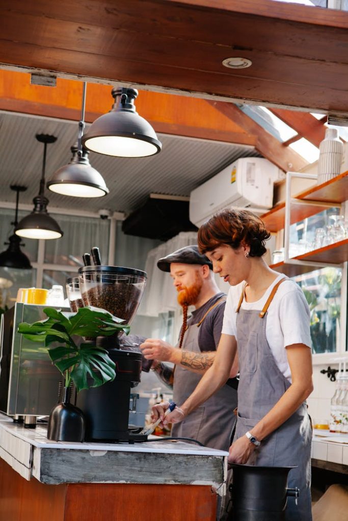 Two baristas preparing coffee drinks in a modern café with natural light.