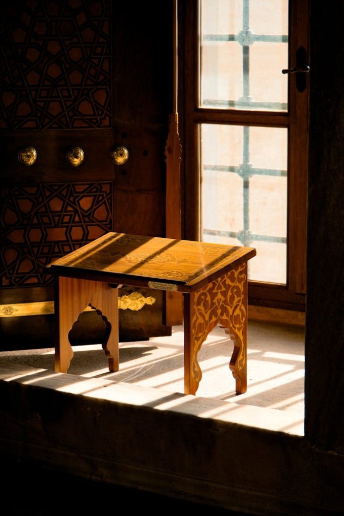 A beautifully carved wooden table illuminated by natural light in a serene indoor setting.
